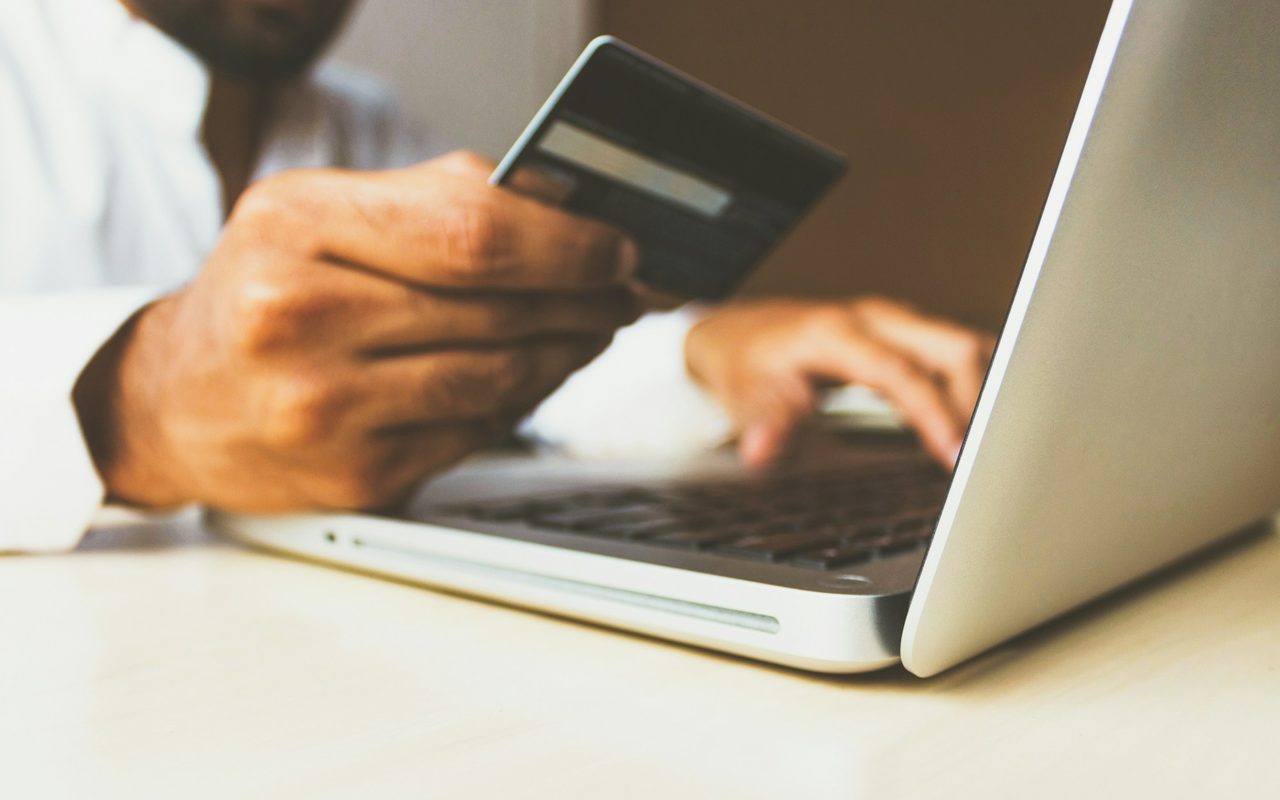 Laptop başında kredi kartıyla online alışveriş yapan kişi — e-ticaret sitesi kurma rehberi